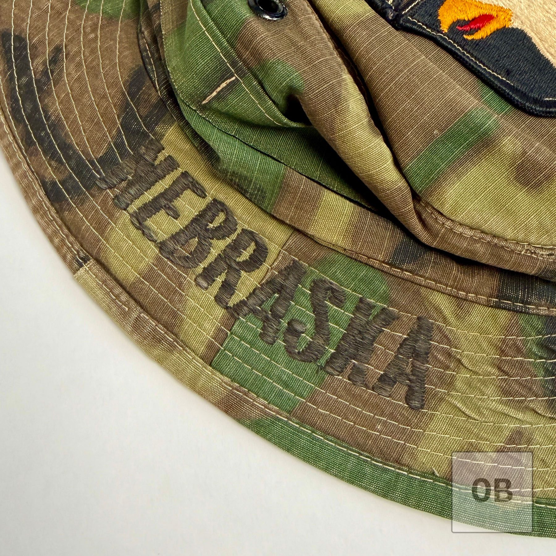 Close-up of NEBRASKA embroidered in dark thread directly onto the ERDL camouflage brim.