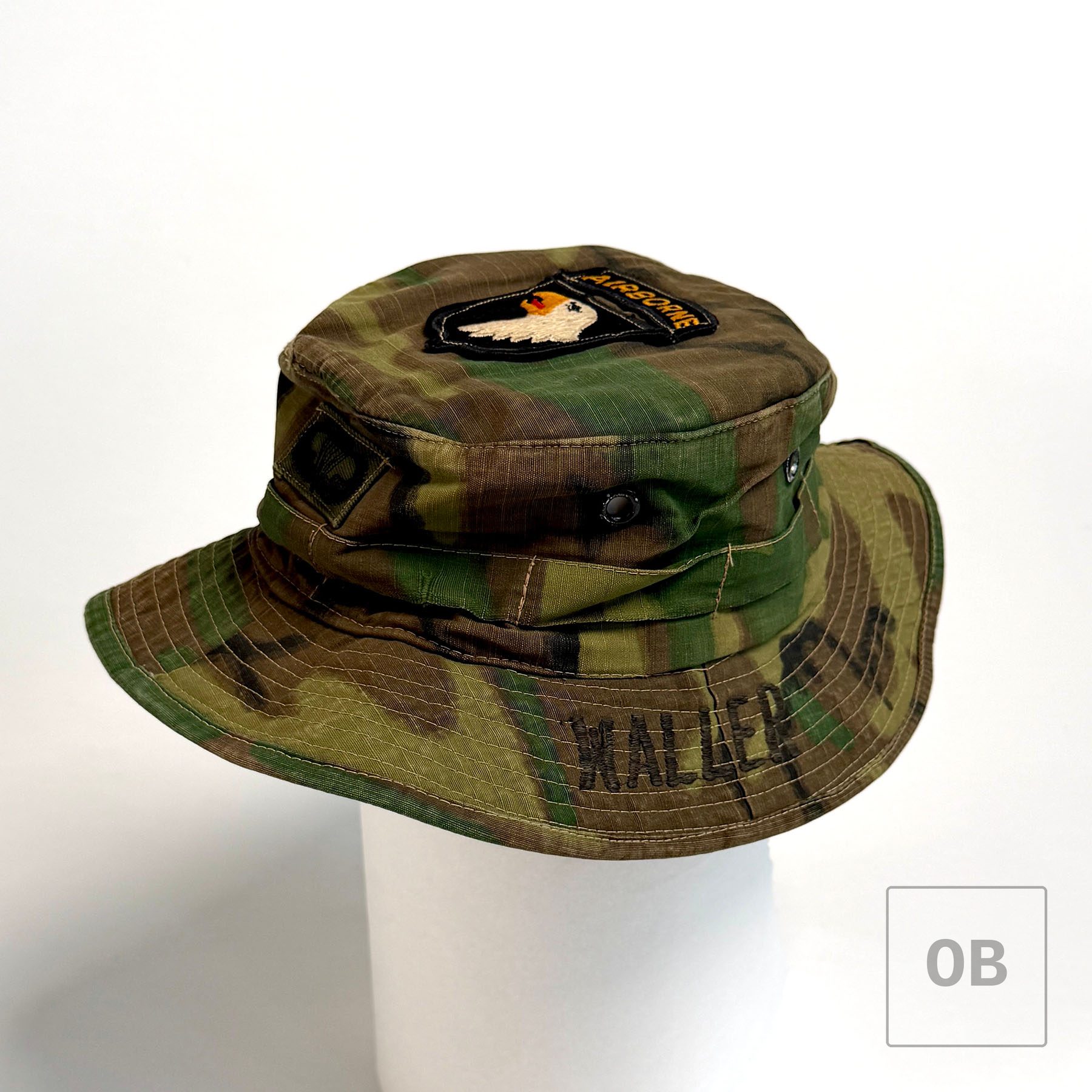 Three-quarter view of the ERDL boonie hat on a white display form, showing WALLER embroidered on the brim, the 101st Airborne insignia on the crown, and subdued parachutist wings on the side.