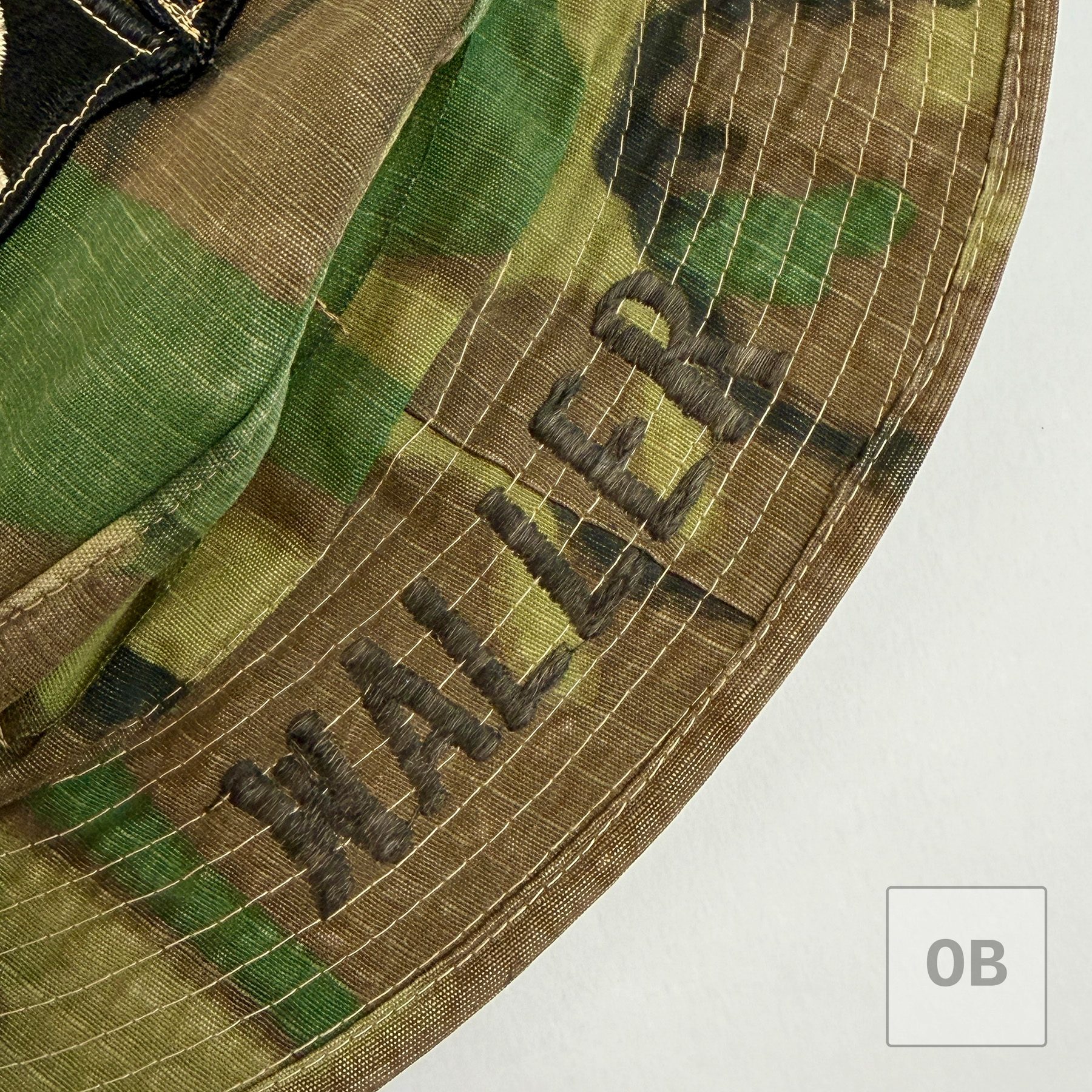 Close-up of WALLER embroidered in dark thread directly onto the ERDL camouflage brim, stitched over the brim's rows of quilting.