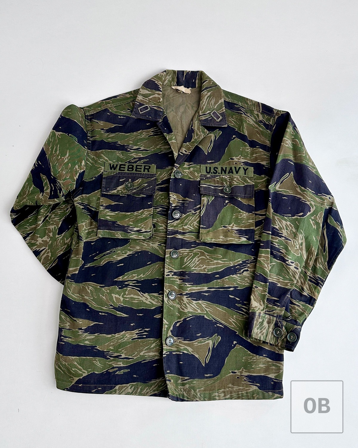 Front view of tigerstripe camouflage jacket with Navy tape and name tape chain-stitched above the pocket.