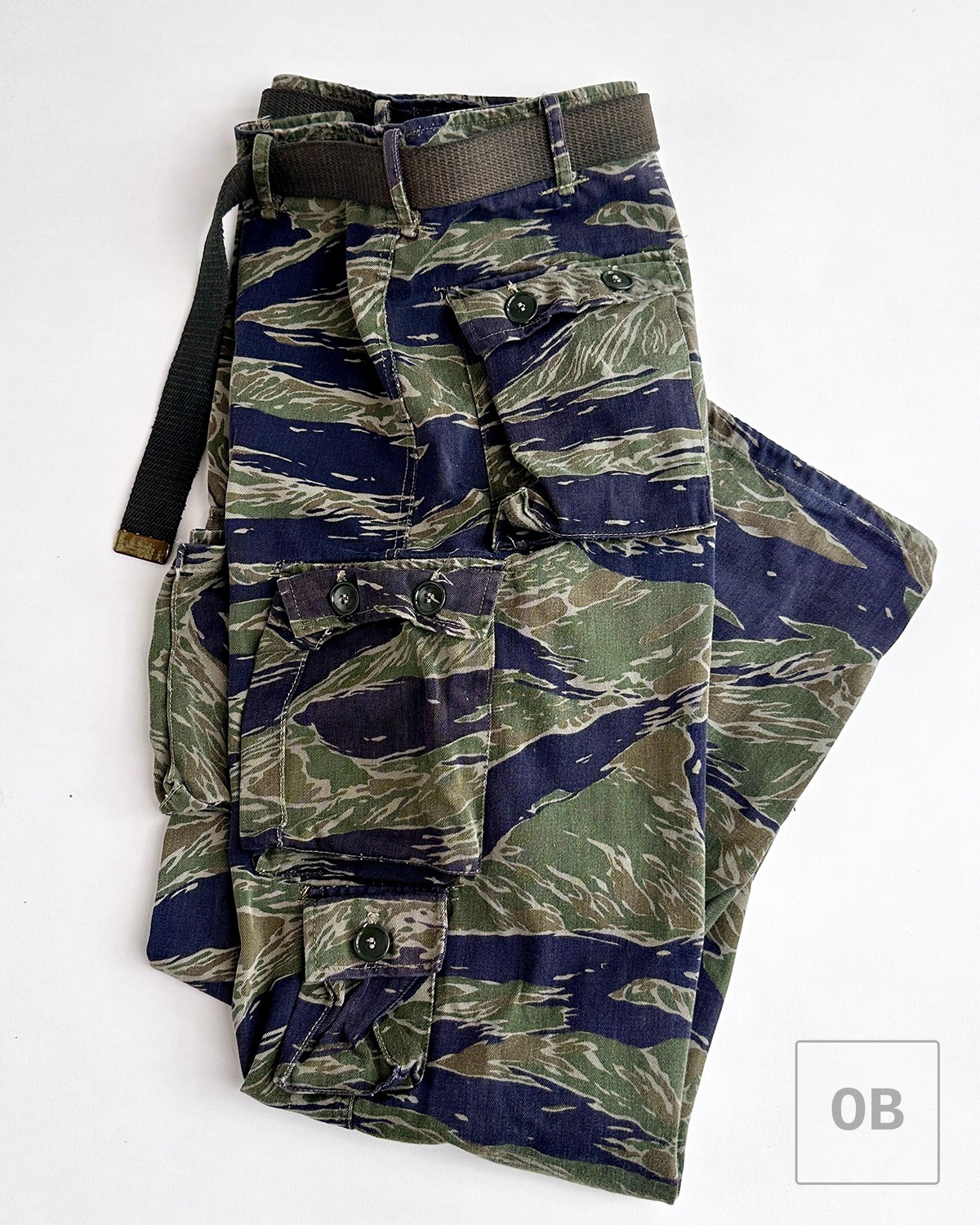 Tigerstripe camouflage trousers with issued web belt threaded through the loops.