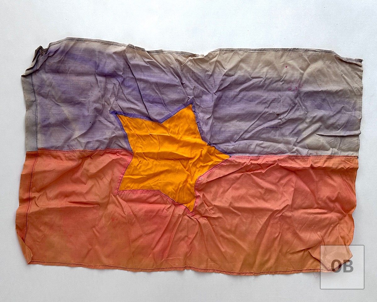 Captured Viet Cong flag with sun-bleached dye faded to pale streaks.