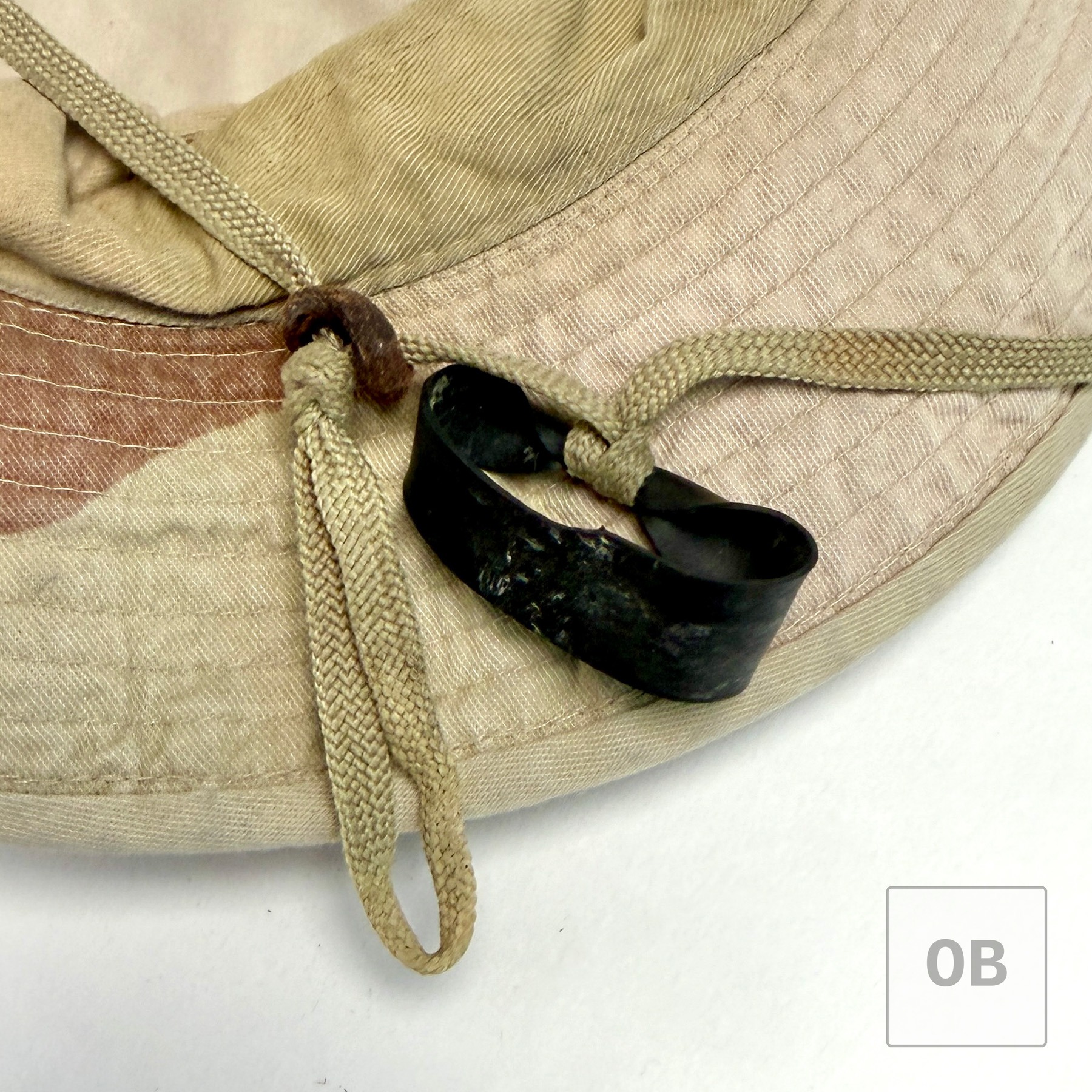 Detail of the three-color desert hat's chin cord, fitted with a loop of black rubber inner tube as a modification.