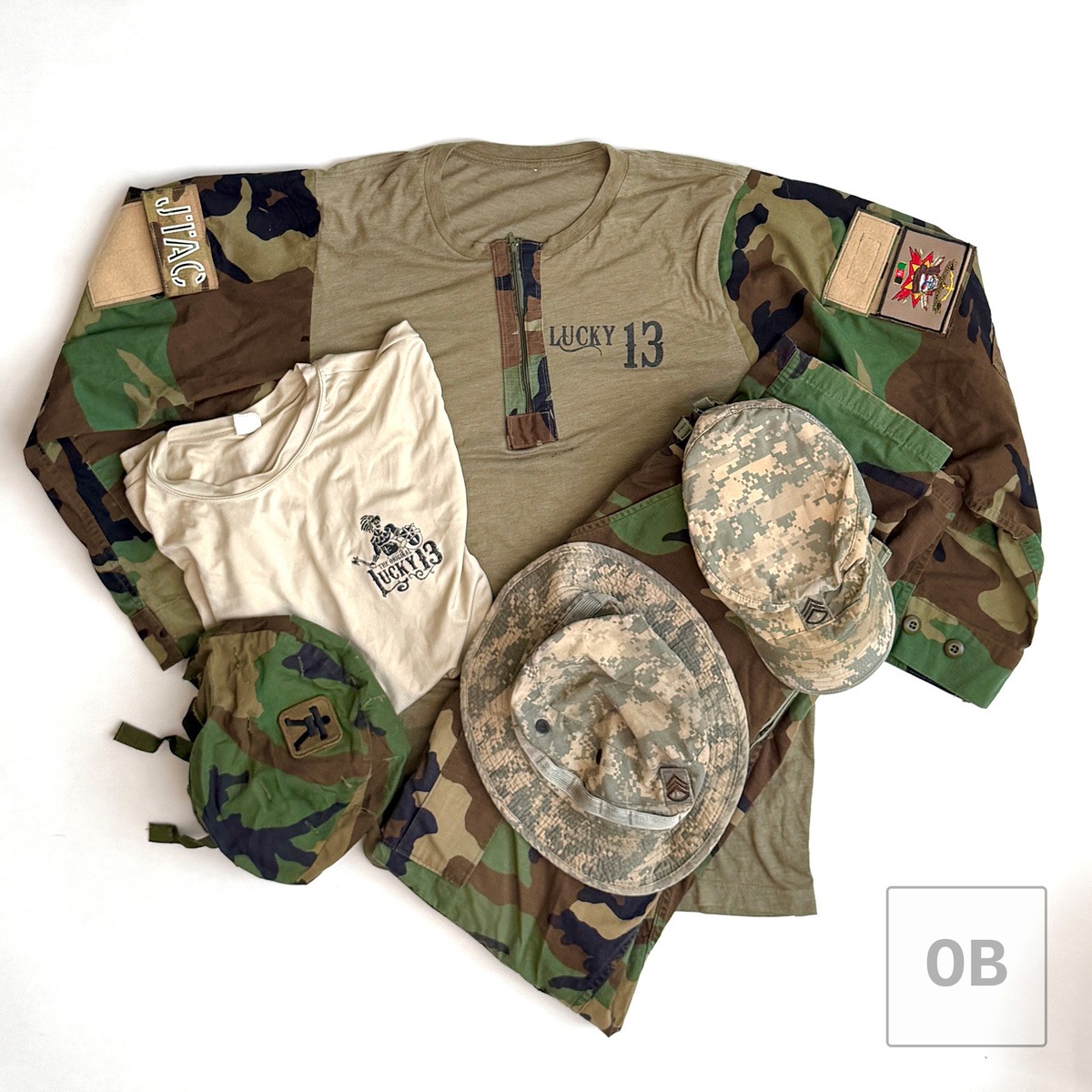 Combat top, Lucky 13 t-shirt, modified BDU trousers, boonie hat, patrol cap, and 509th helmet cover laid flat together.