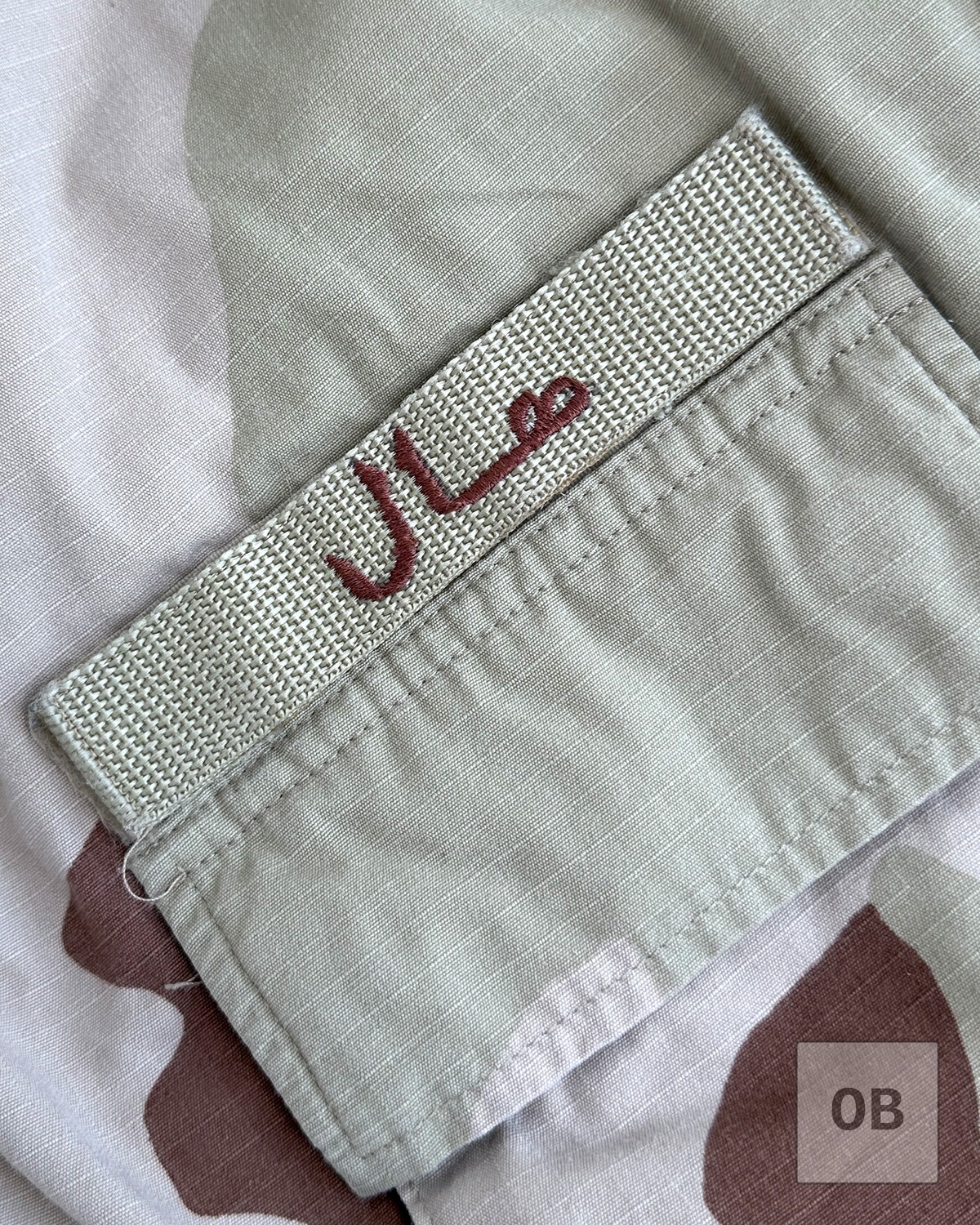 Farsi name tape embroidered in cinnamon thread on tan nylon webbing.