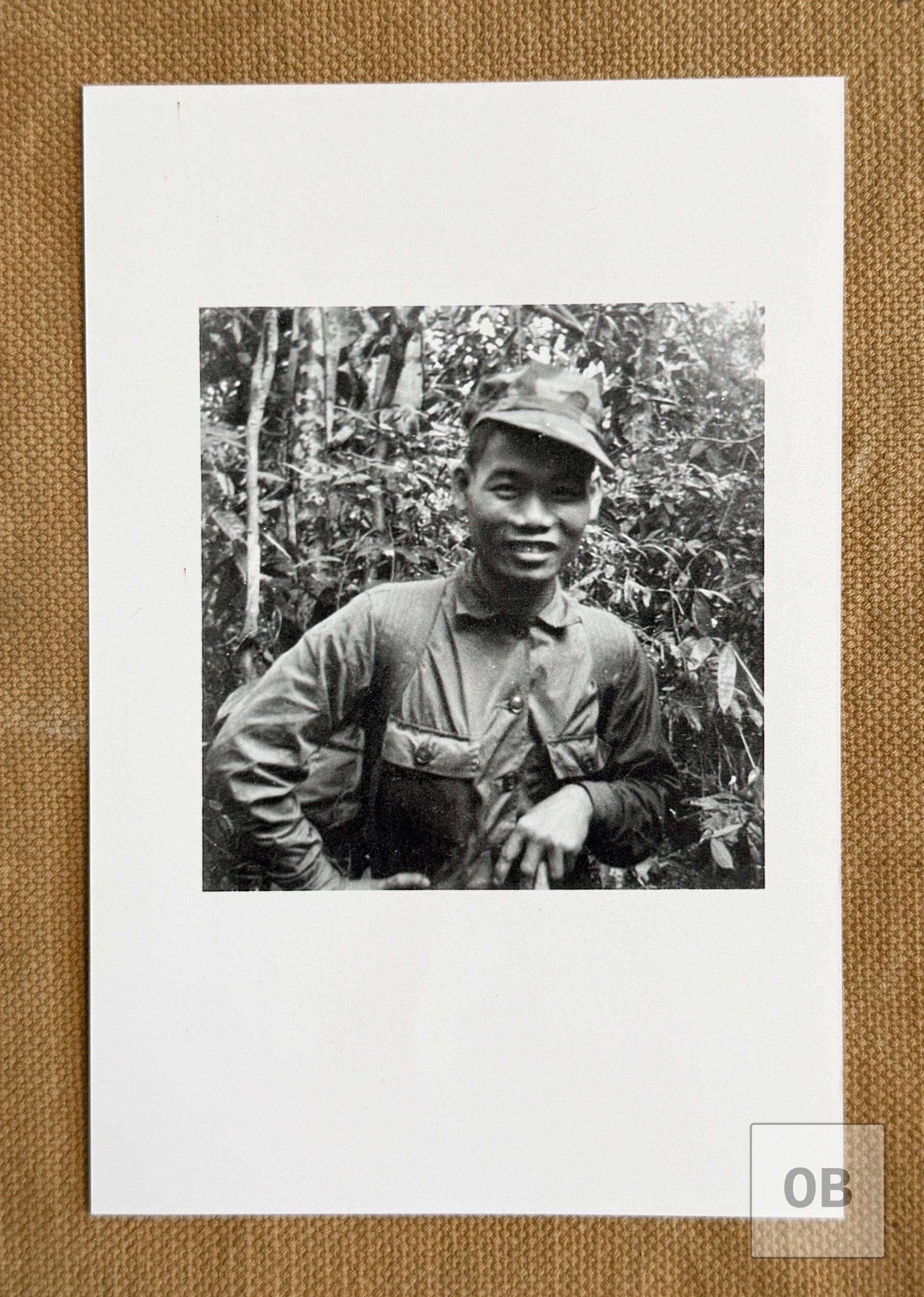 A smiling Rhade soldier of the 1st Mobile Strike Force in a patrol cap, standing in the jungle.