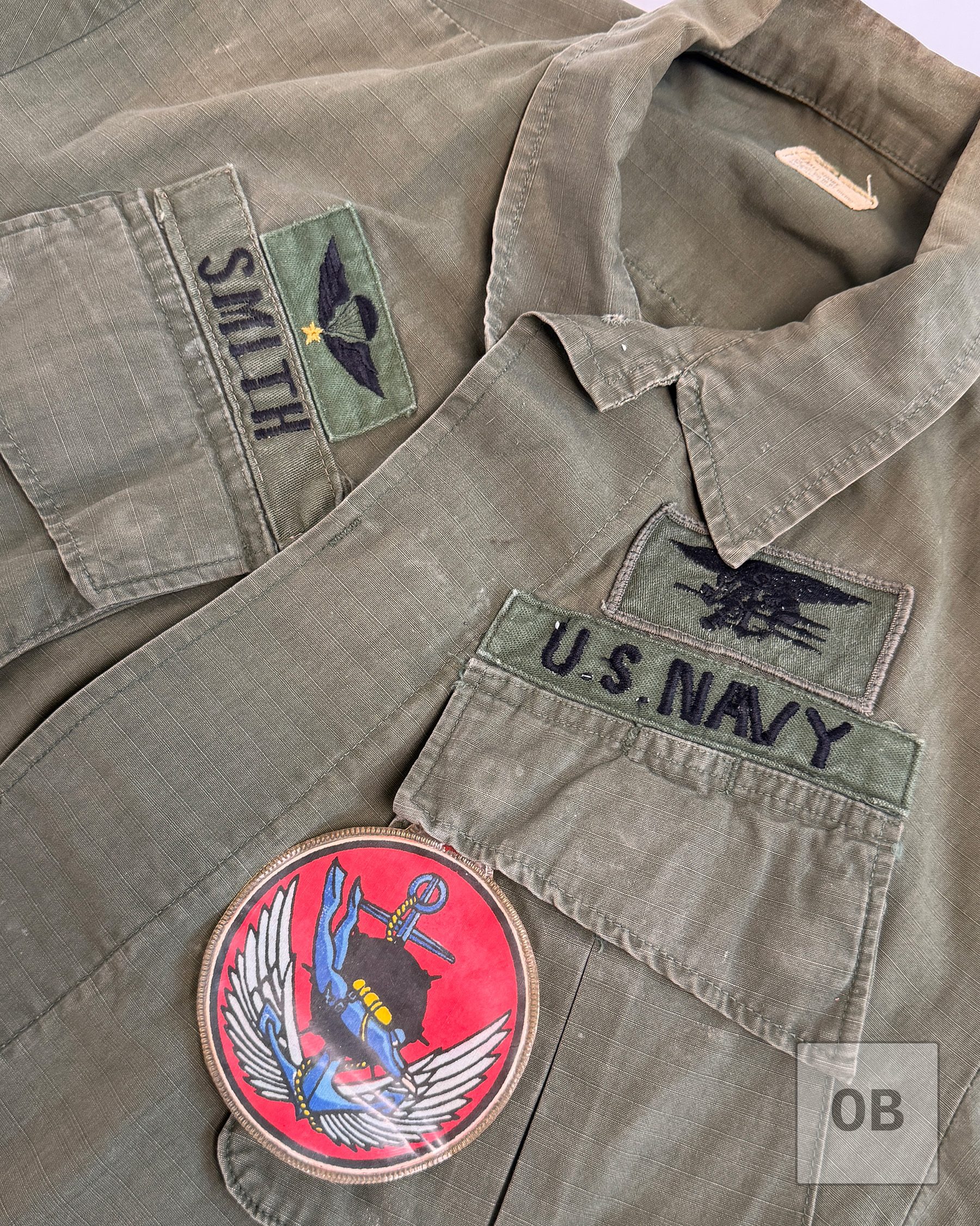 Chest of a Vietnam War SEAL Team 1 OD jungle jacket showing the SMITH tape, South Vietnamese jump wings, SEAL Trident, U.S. NAVY tape and LDNN patch.