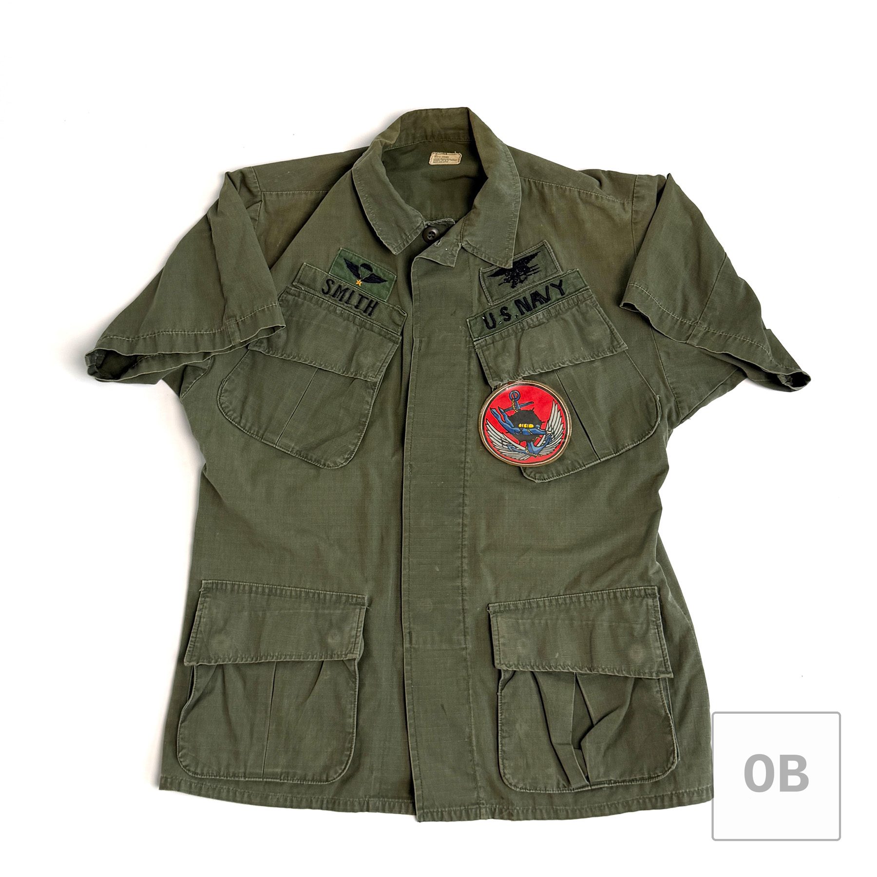 Vietnam War Navy SEAL Team 1 OD jungle jacket, 1968-dated, sleeves shortened, with theater-made SMITH and U.S. NAVY tapes, South Vietnamese jump wings, SEAL Trident and LDNN patch.